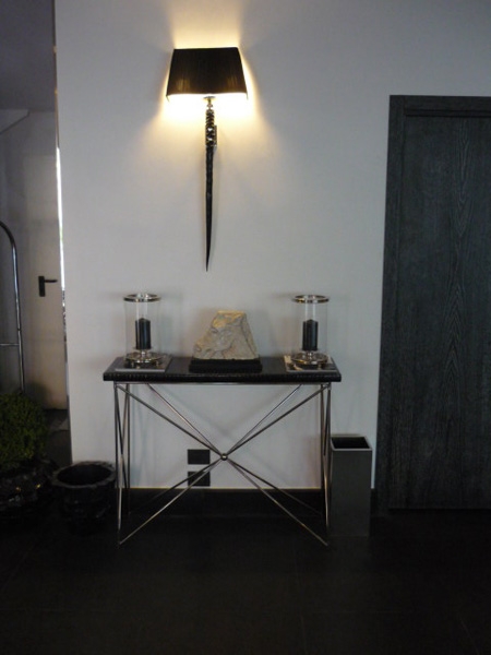 In the big Hall of the Santa Margherita Palace, the console FILO with black eel top and base FILO in brass nikel plated; on the top a pair of clear crystal CYLINDRICAL CANDLESTICKS with metal bases, and on the wall real horn ORYX wall lamp with black shade.